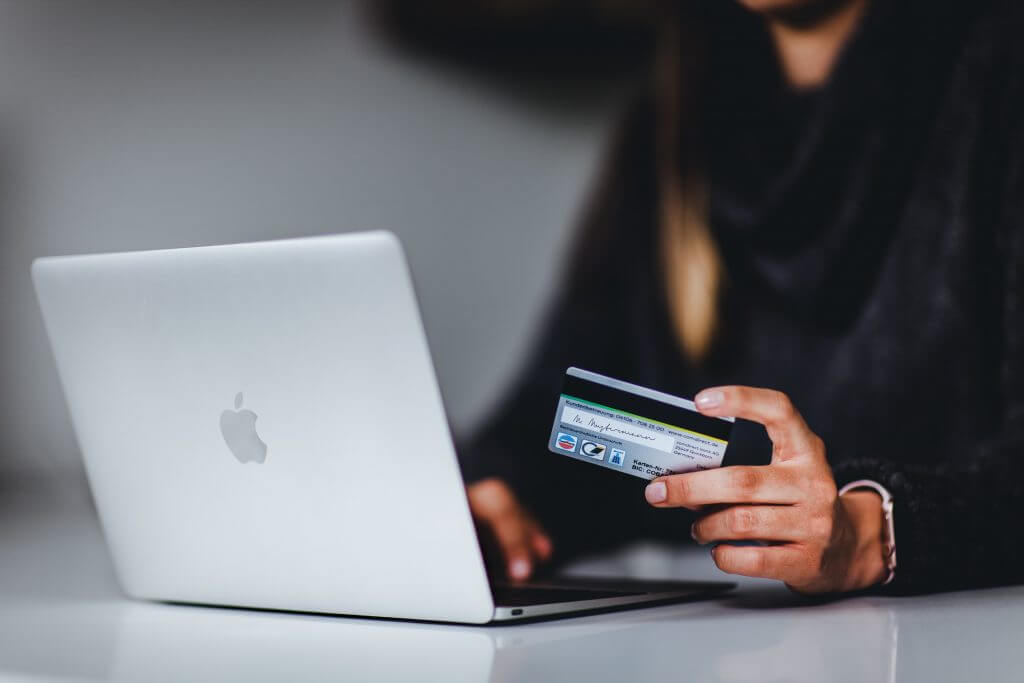 woman holding credit card while at computer